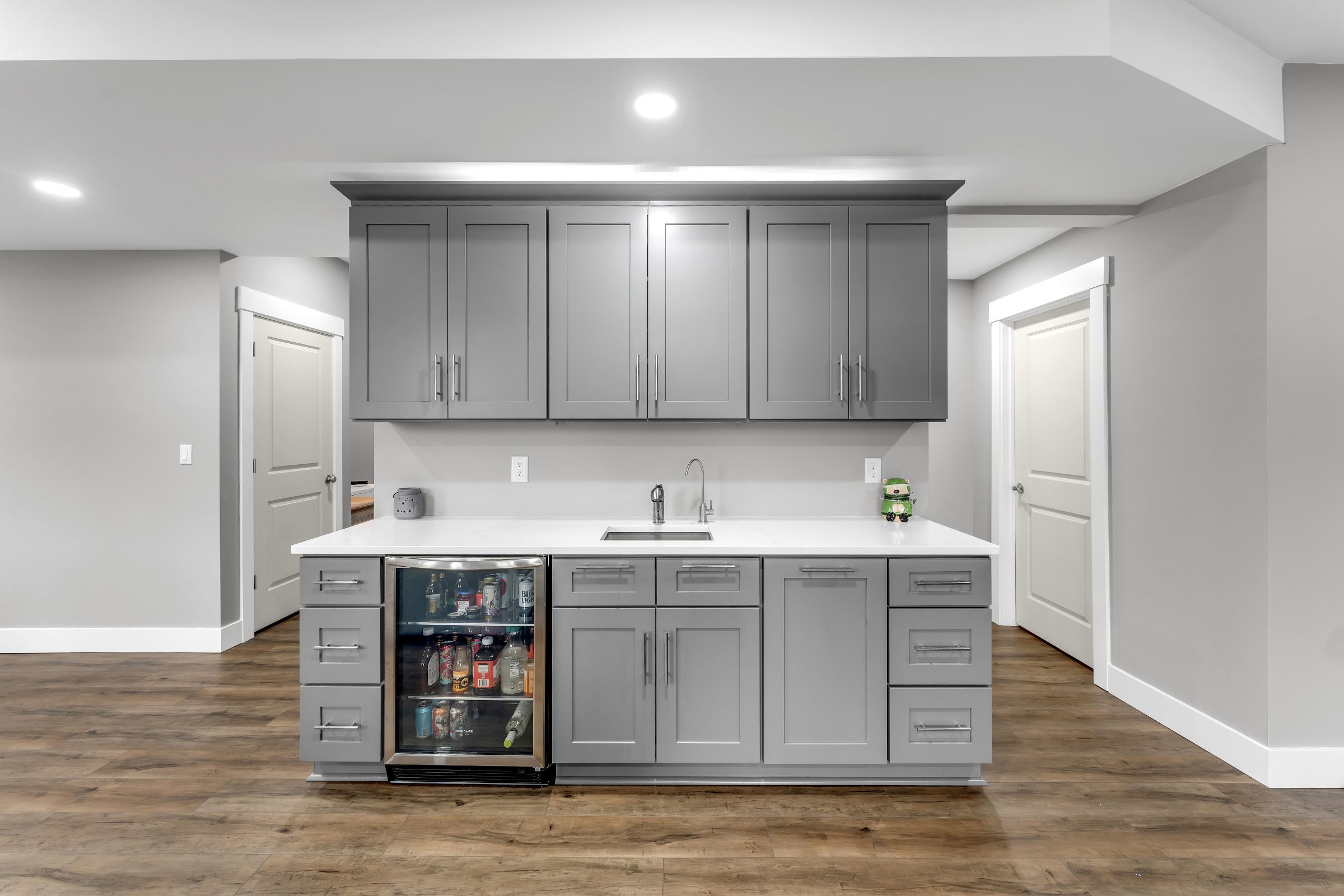 Custom wet bar with beverage refrigerator and gray cabinetry