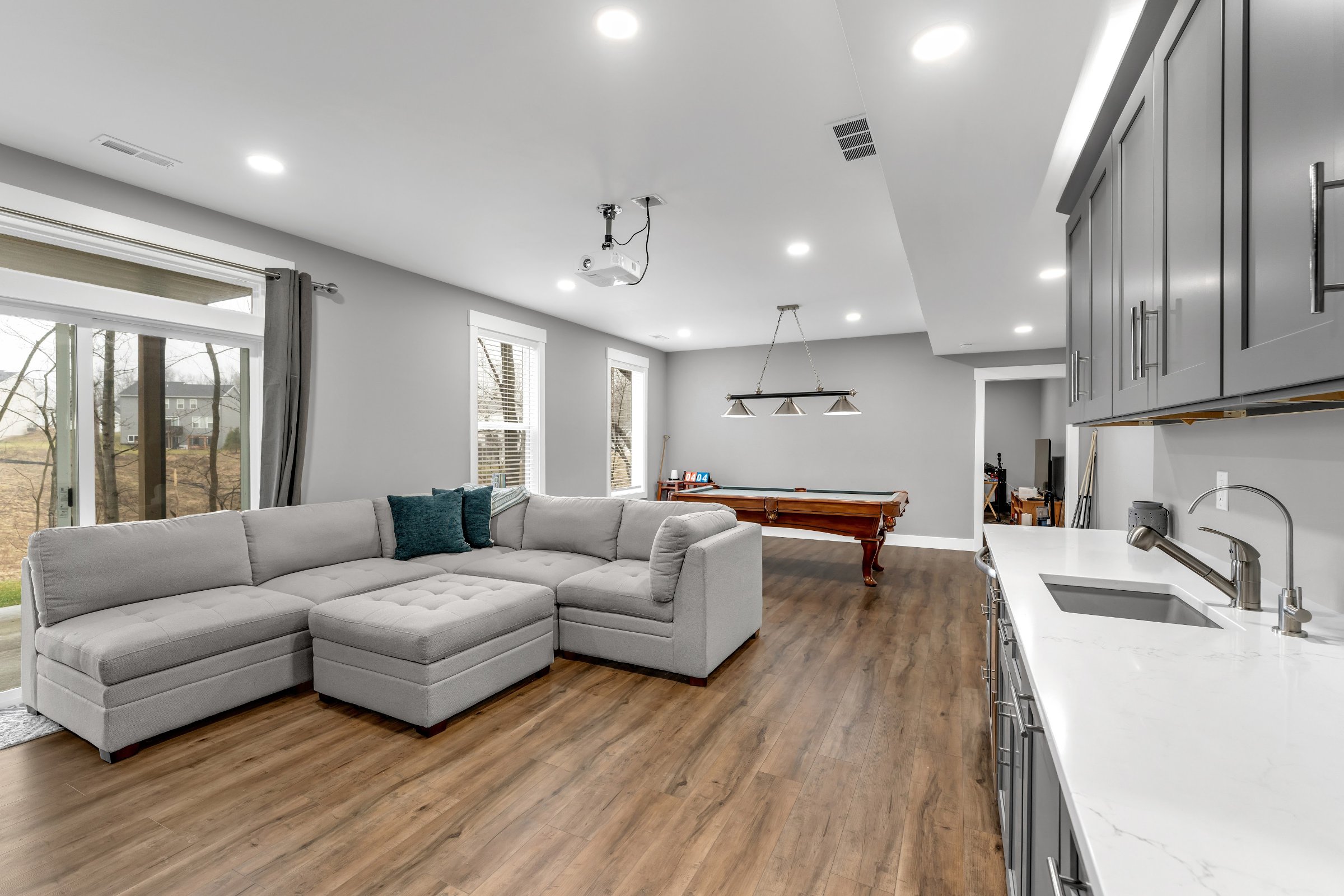 Sectional seating area in finished basement with recessed lighting