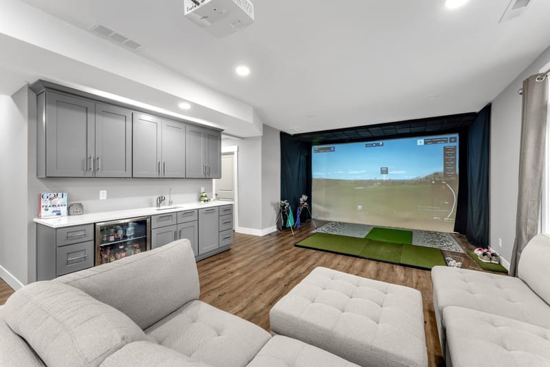 Finished basement — golf simulator lounge with wet bar and sectional seating