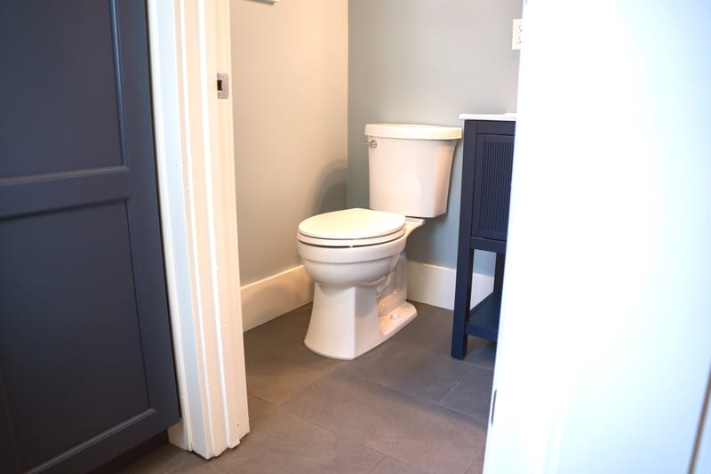 Bathroom remodel — navy vanity, gold fixtures, subway tile shower