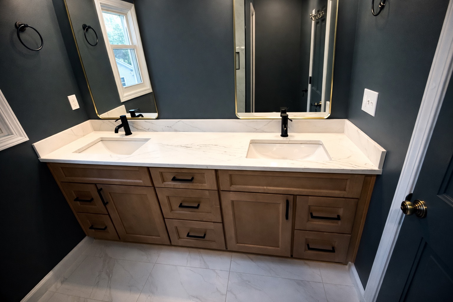 Modern Sophistication bathroom wide view — dark marble tile, frameless glass shower, matte black fixtures, wood vanity